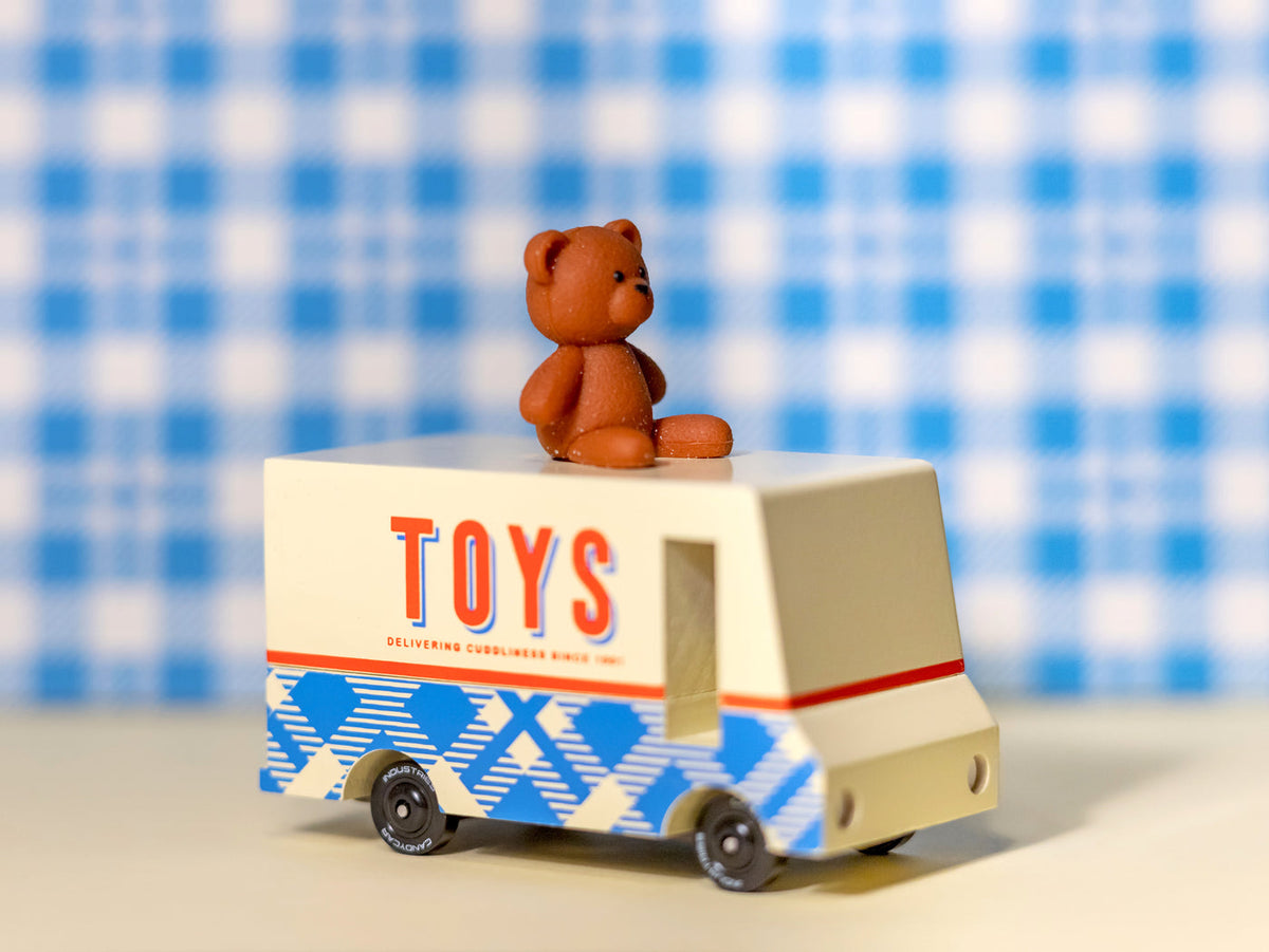 Toy truck with a teddy bear on top against a blue and white checkered background