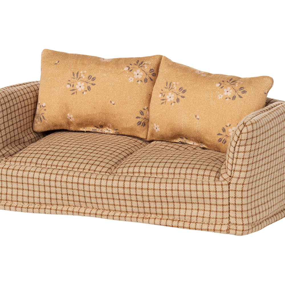 Beige checkered sofa with floral-patterned cushions on a white background