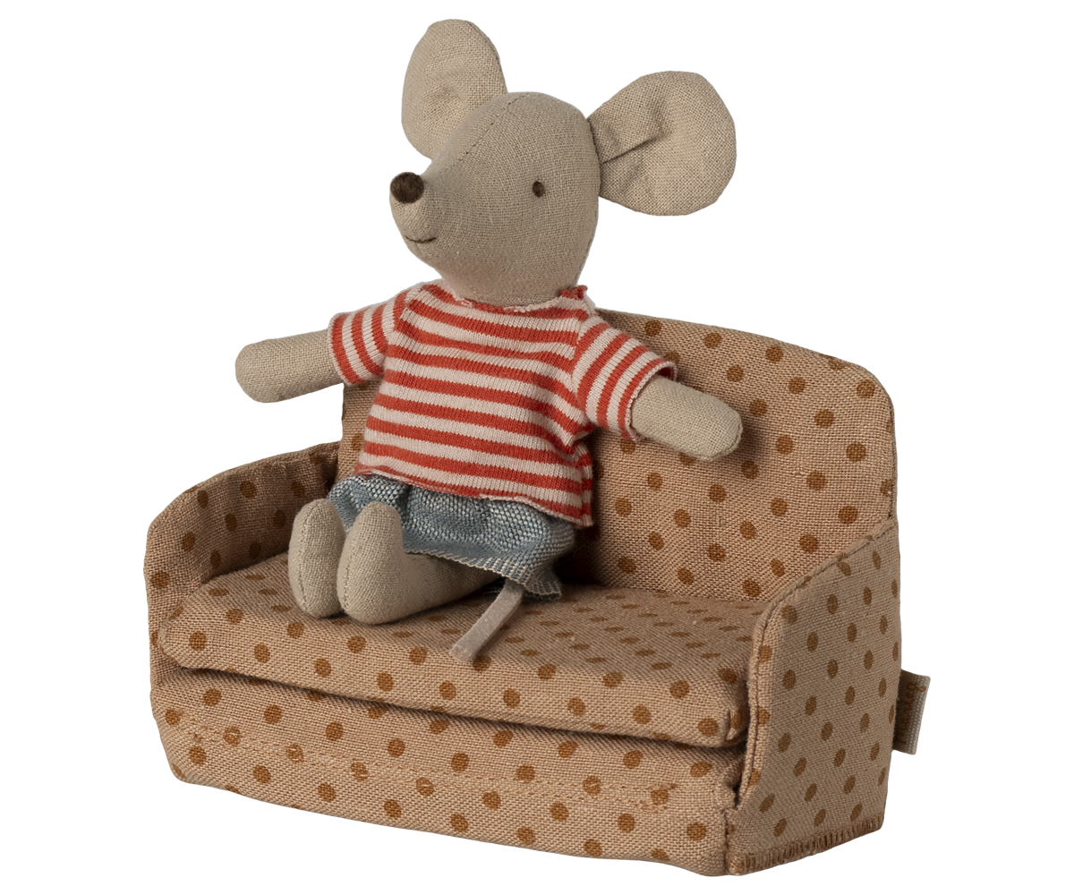 Stuffed mouse toy in a striped shirt sitting on a polka dot couch with a white background