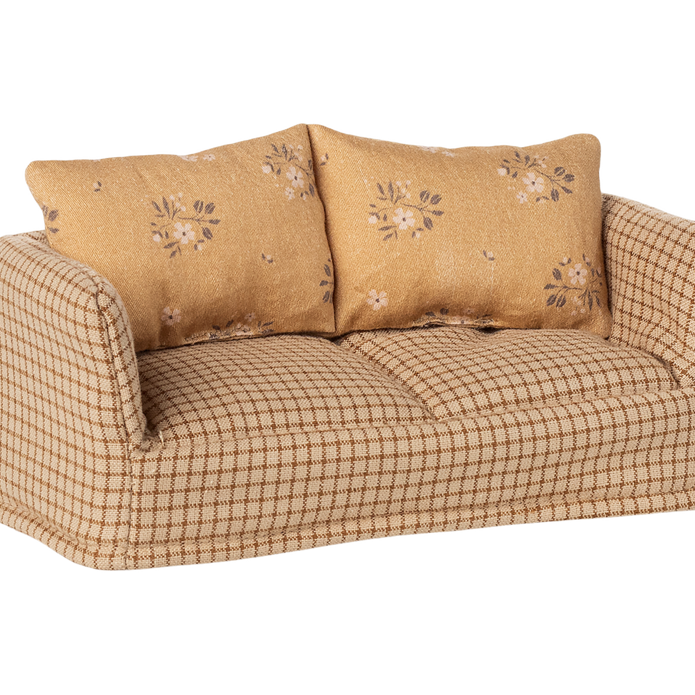 Beige checkered sofa with floral-patterned cushions on a white background