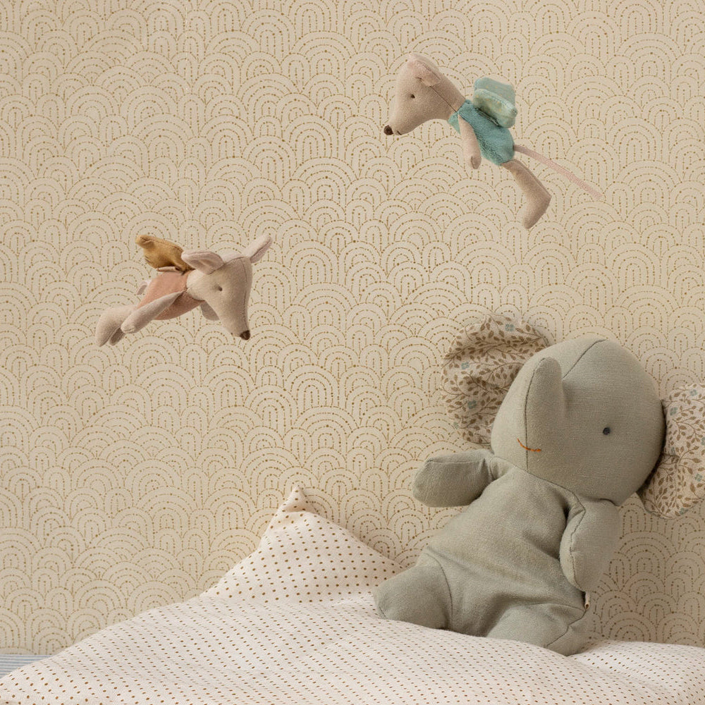 Children's room with stuffed animals on a bed against a patterned wall.