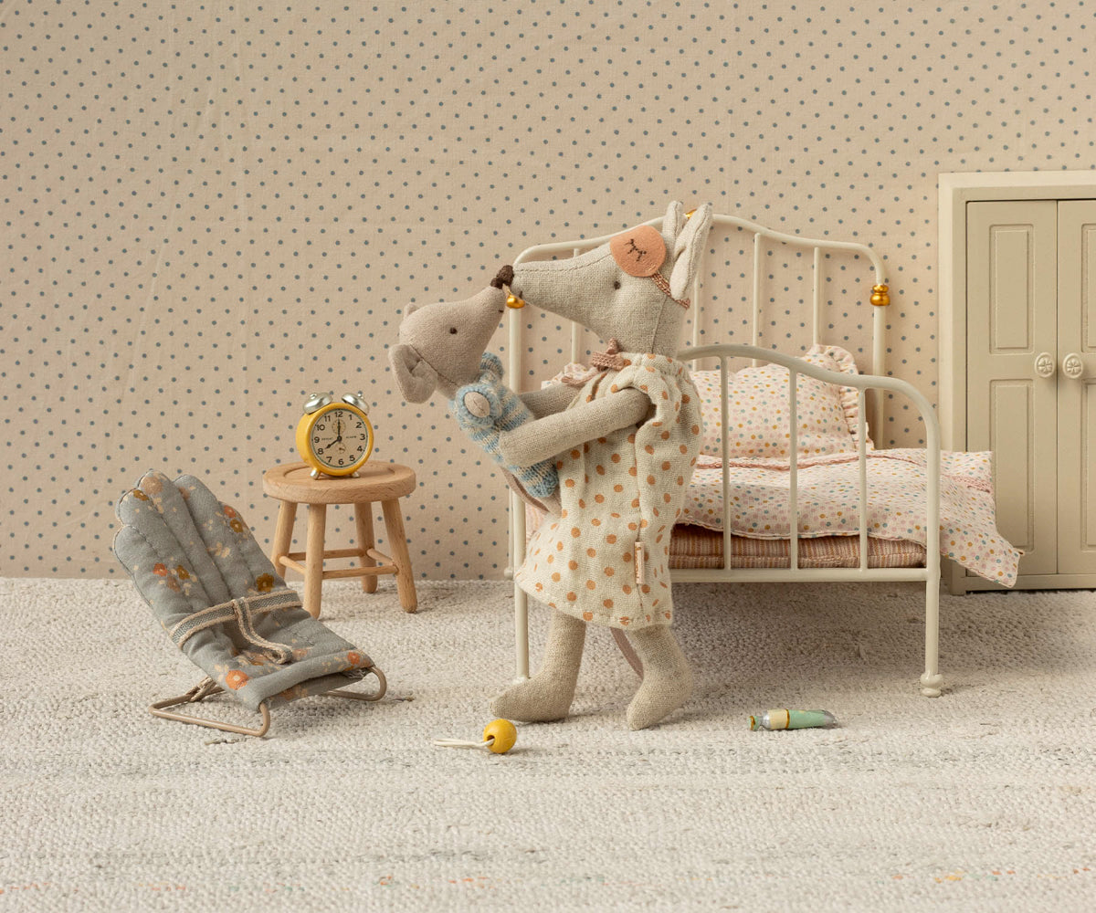 Stuffed animal mouse in a polka dot room with a bed and chair.
