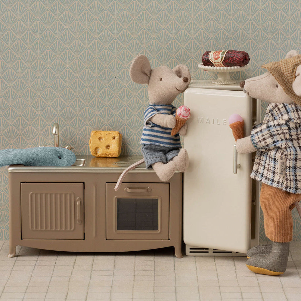 Two toy mice in a kitchen setting with a refrigerator and sink.