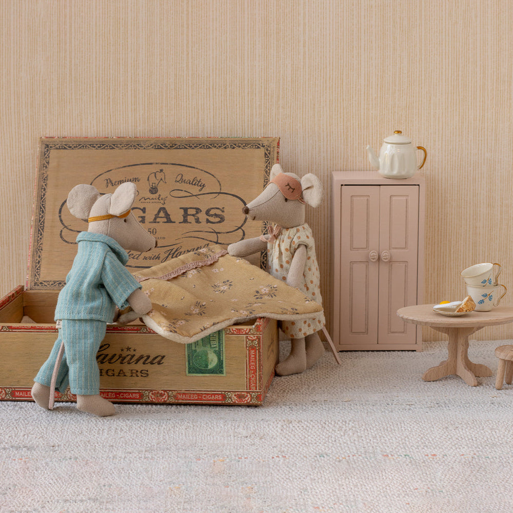 Maileg Mum mouse standing next to a vintage cigar box where Dad mouse sits inside, set against a miniature room scene with a small wardrobe, table, and teapot.