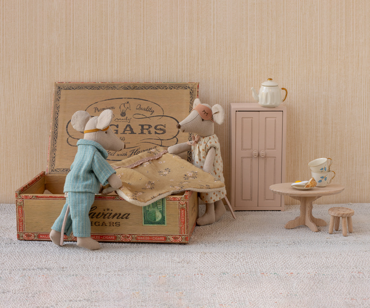 Maileg Mum mouse standing next to a vintage cigar box where Dad mouse sits inside, set against a miniature room scene with a small wardrobe, table, and teapot.