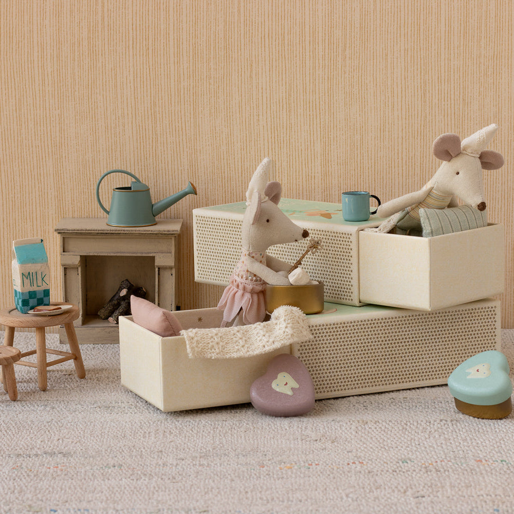 Miniature dollhouse scene with toy animals and furniture on a neutral background