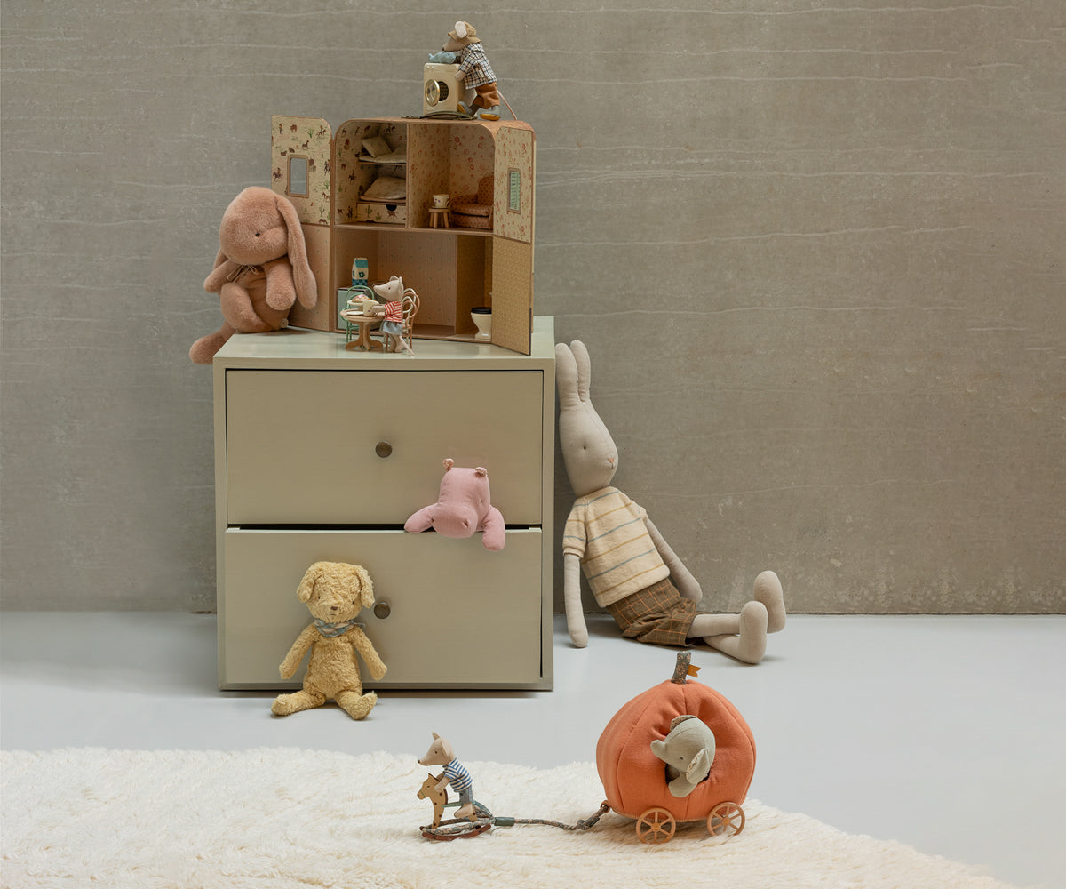 Children's toys and a small wooden dresser against a plain wall.