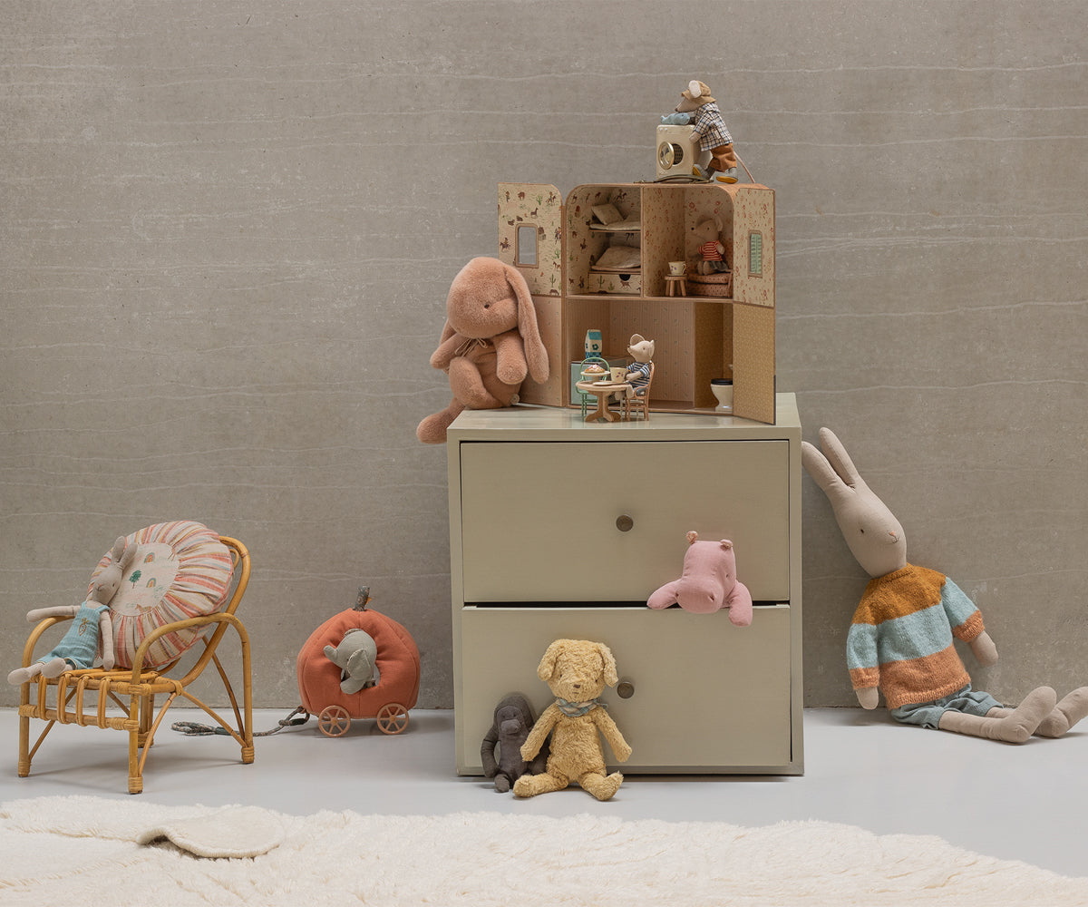 Children's room with toys and a small dresser against a beige wall.