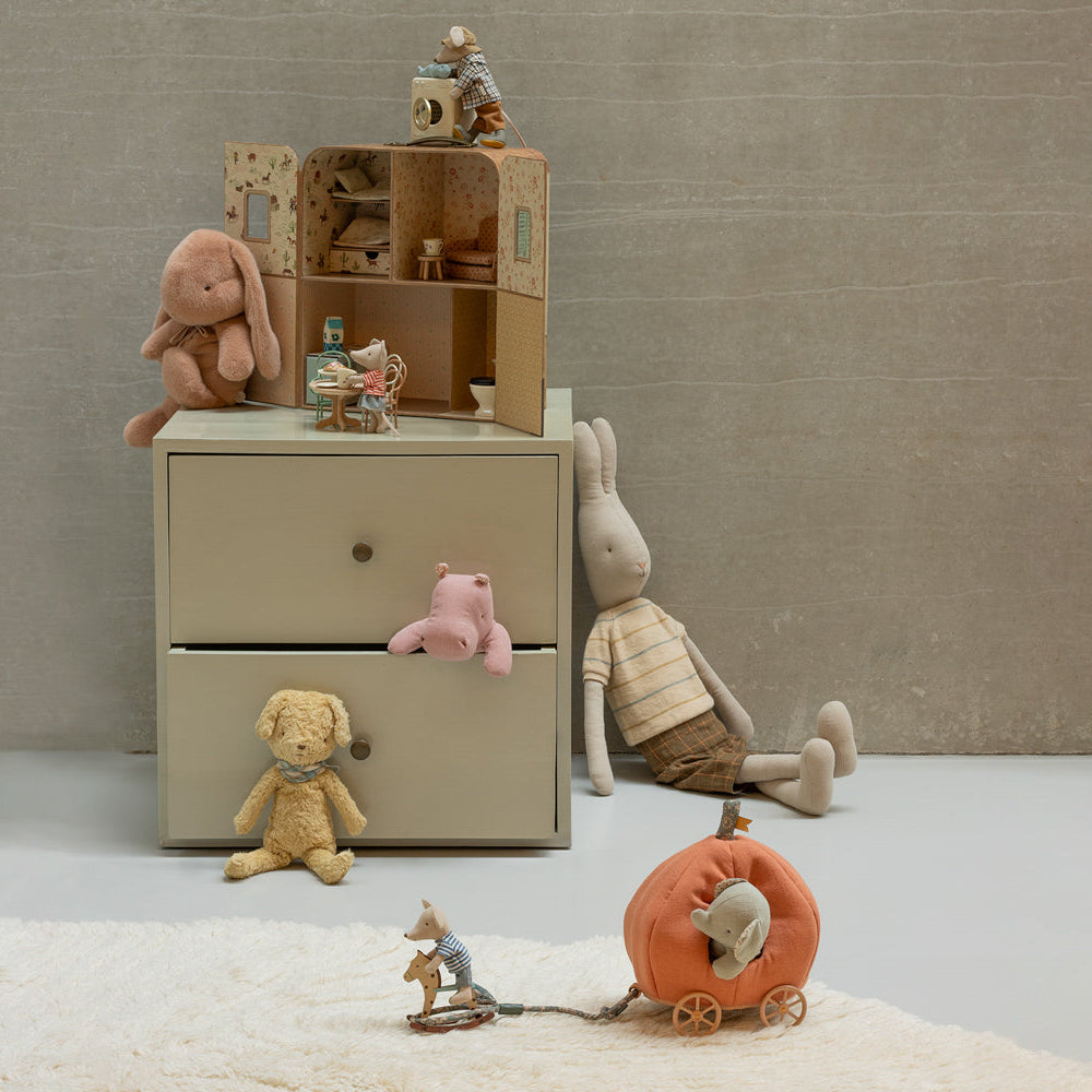 Children's toys and a small wooden dresser against a plain wall.