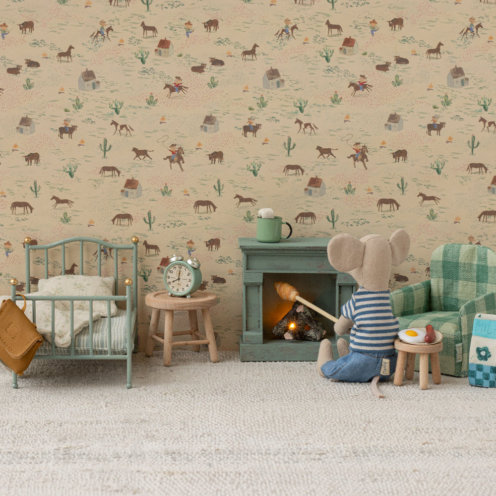 Two Maileg mouse toys in a miniature room setting with patterned wallpaper and carpet; one mouse on the left operates a toy vacuum cleaner next to a thermos and canister, while another mouse on the right stands beside a mint green single bed and a matching storage cabinet with a blue lantern on top.