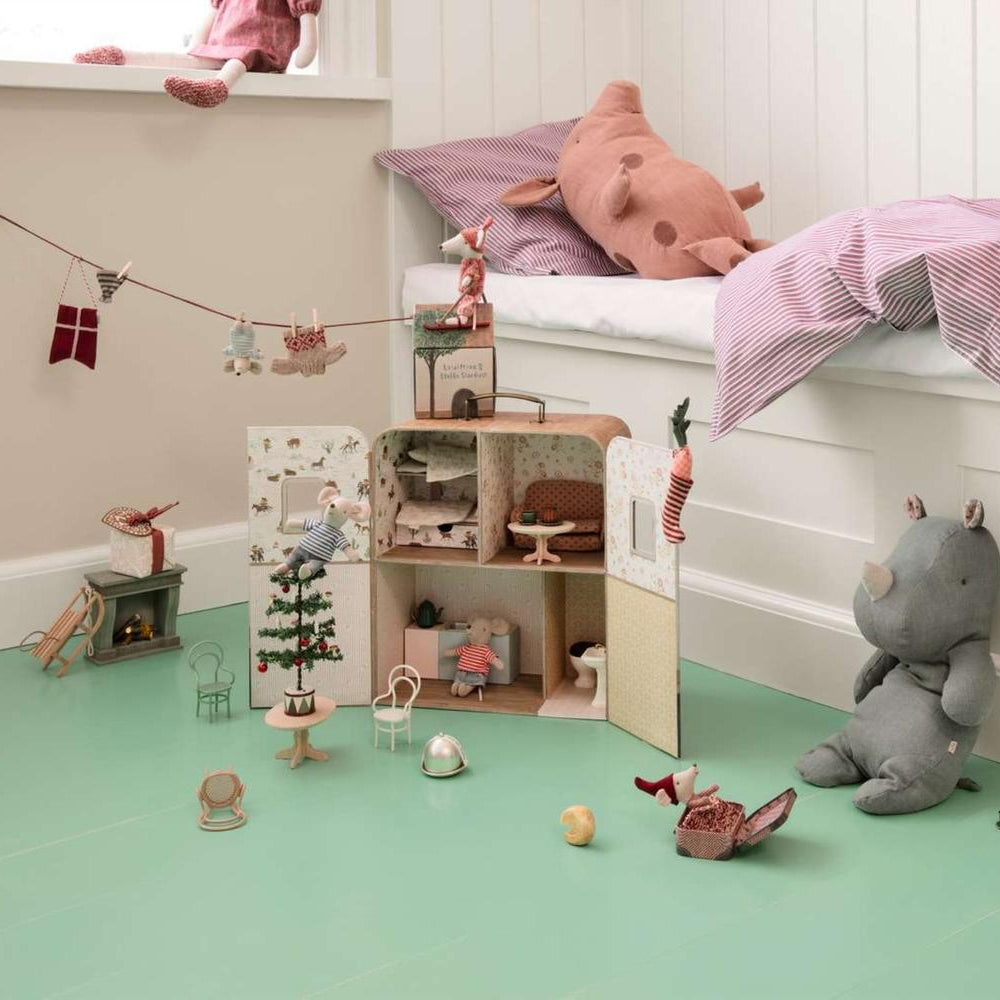 Children's room with a dollhouse, toys, and a plush elephant on a green floor.