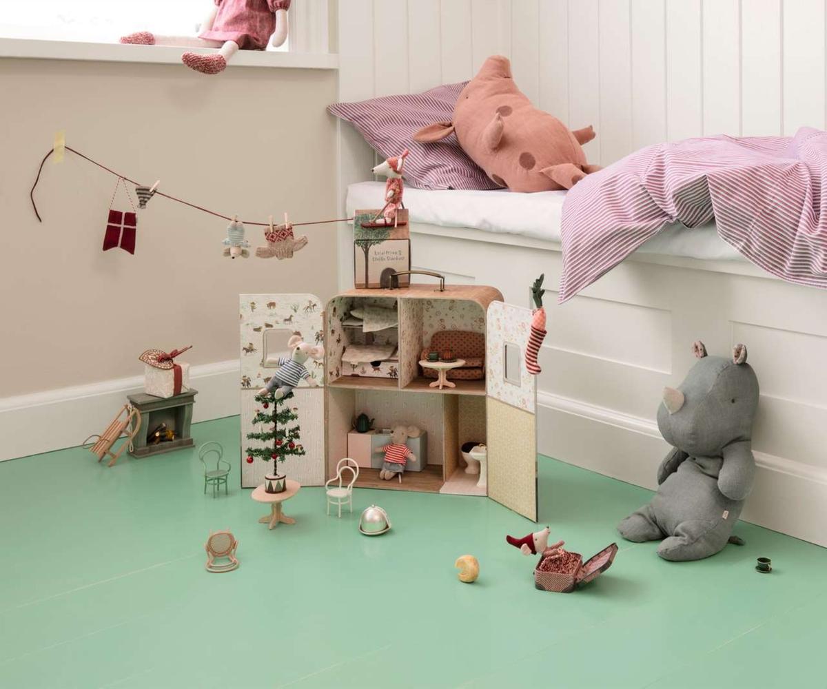 Children's room with a dollhouse, toys, and a plush elephant on a green floor.