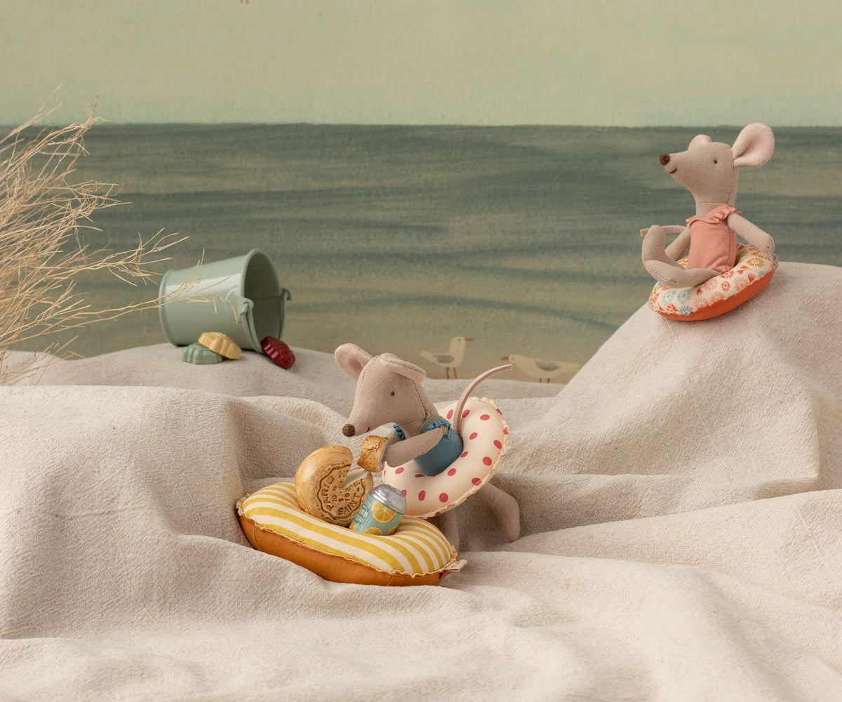 Two toy mice on beach towels with beach accessories