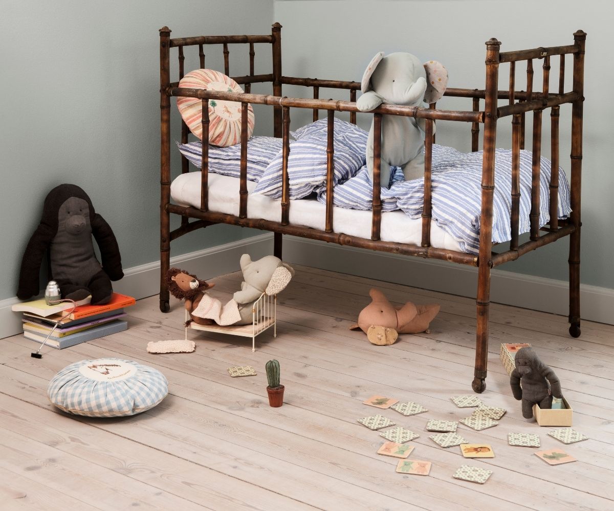 Children's room with wooden crib, toys, and books on a light wood floor.