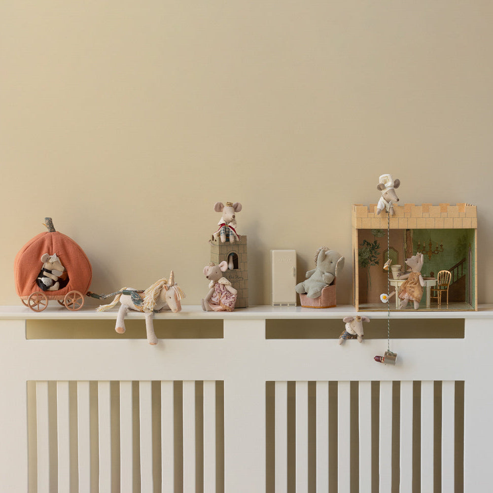 Decorative shelf with small figurines and toys on a white radiator against a beige wall.