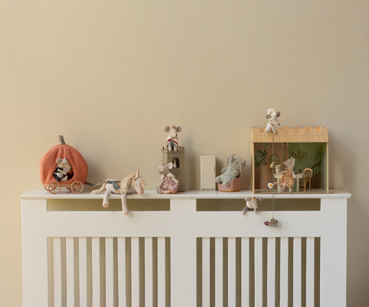 Decorative shelf with small figurines on a white radiator against a beige wall
