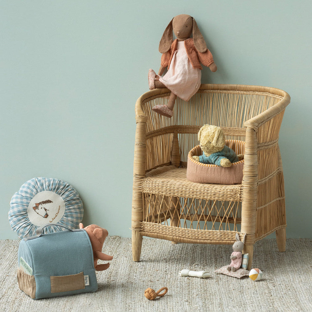 Wicker chair with toys against a light green wall