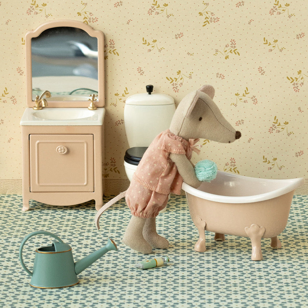 Toy mouse in a bathtub with bathroom furniture and decor in the background