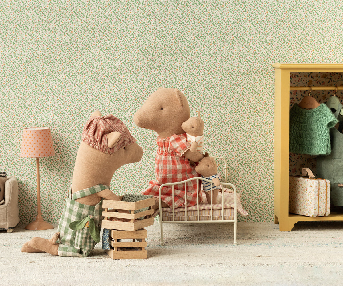 Two plush toys in a room with a floral wallpaper and a yellow cabinet.
