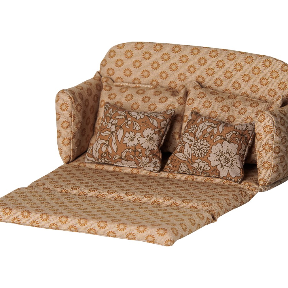 A miniature ocher fabric sofa bed pulled out into a bed for a toy mouse house, featuring a retro floral pattern in shades of brown and cream, with matching back cushions and side pillows against a transparent background.