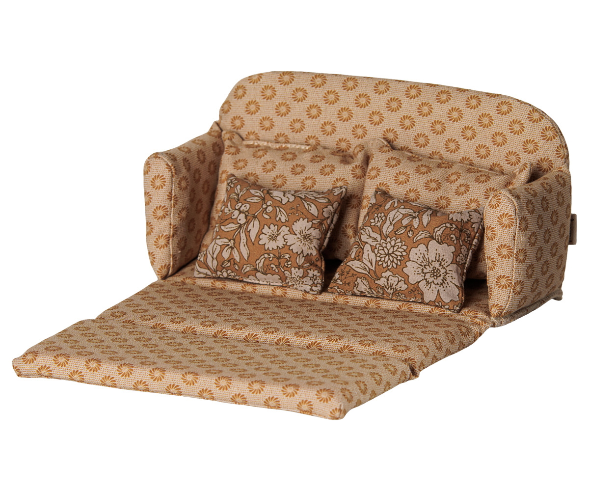 A miniature ocher fabric sofa bed pulled out into a bed for a toy mouse house, featuring a retro floral pattern in shades of brown and cream, with matching back cushions and side pillows against a transparent background.