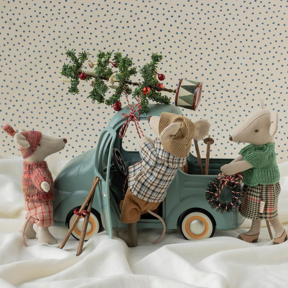 Several Maileg mouse toys gathered around a vintage-style mint-green toy car on a soft, draped white fabric background.