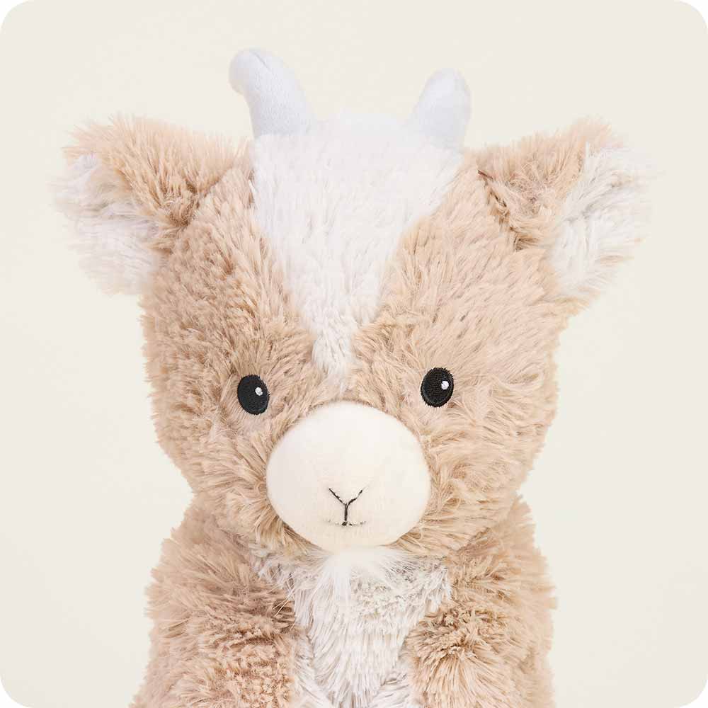 Plush toy resembling a creature with a brown body, white face, and gray horns on a beige background