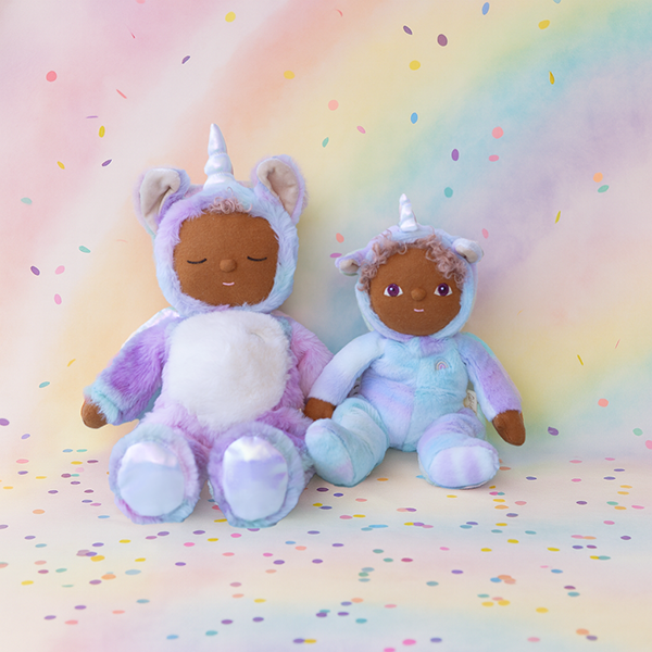 Two plush toys in unicorn costumes on a rainbow-colored background with polka dots.