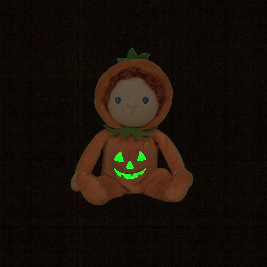 Plush toy in a pumpkin costume with glowing green face on a black background
