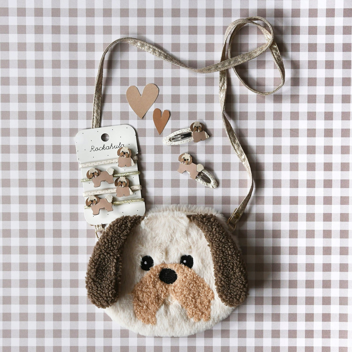 Dog-shaped pouch with a strap and heart-shaped earrings on a checkered background