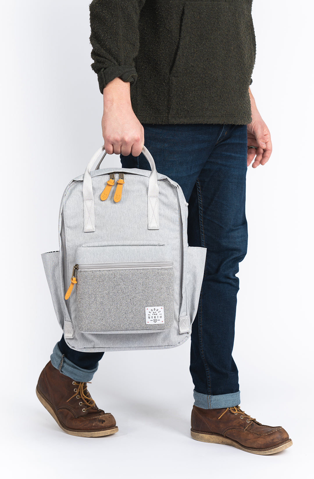 Person holding a gray backpack with a transparent side panel on a white background