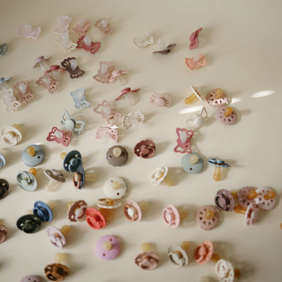 Collection of various baby accessories including pacifiers and hair clips on a light background
