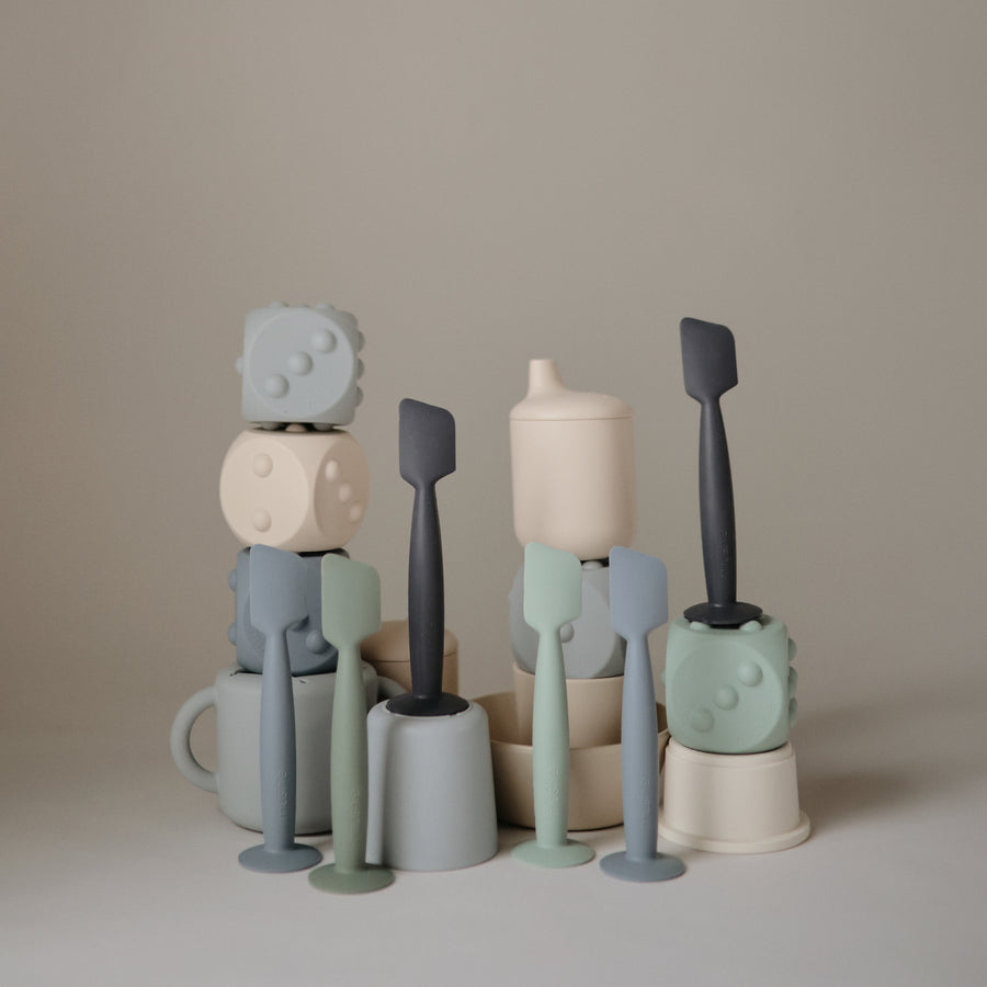 Set of colorful ceramic kitchen utensils on a neutral background