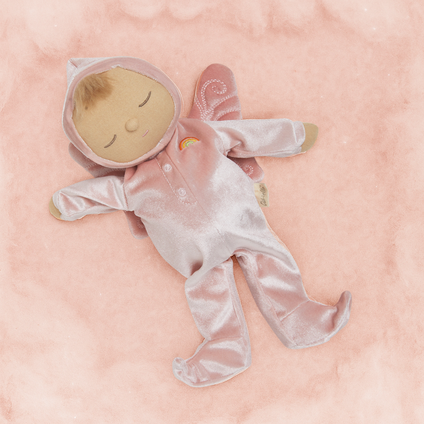 Plush baby doll in a pink outfit lying on a pink blanket