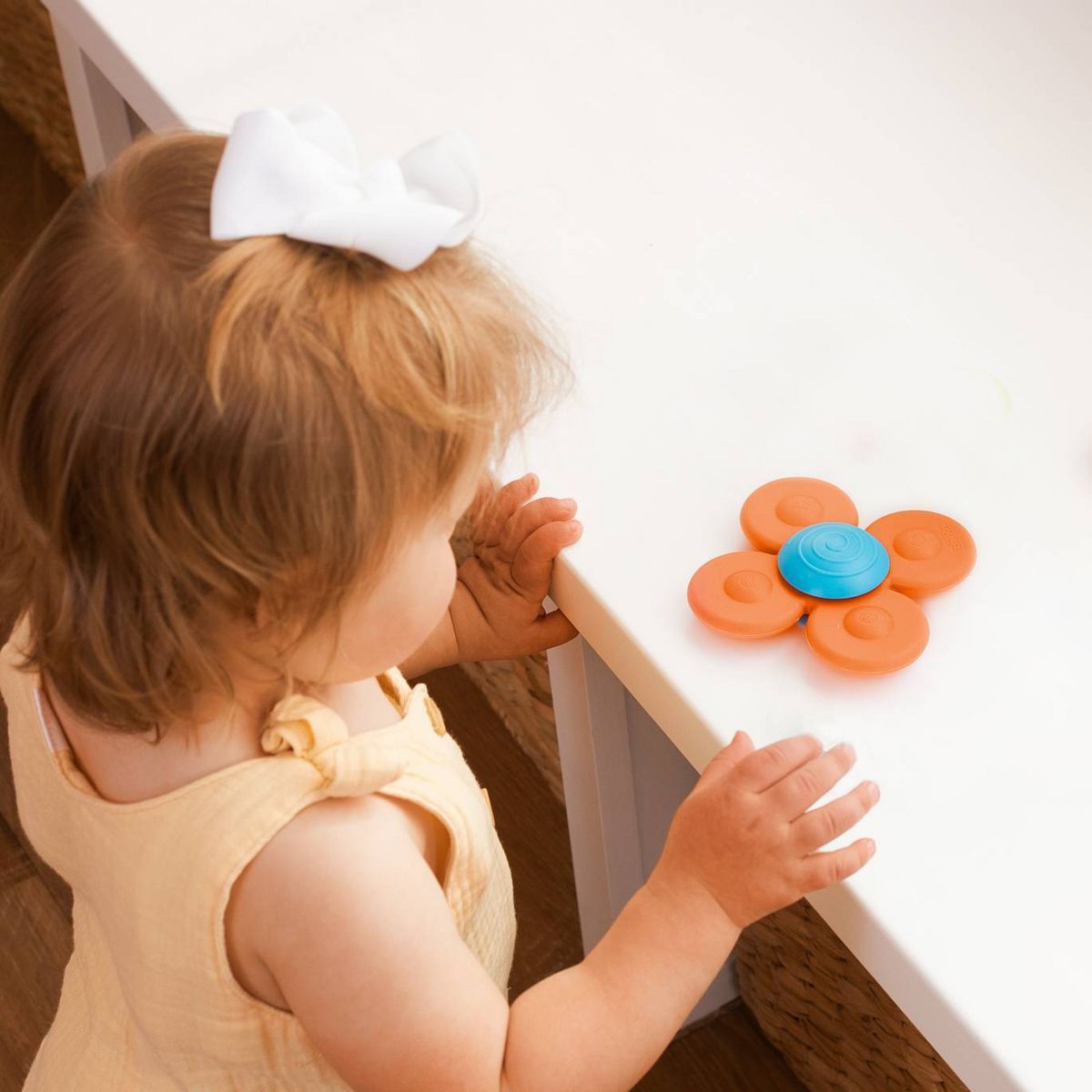 Child interacting with a flower-shaped toy on a white surface
