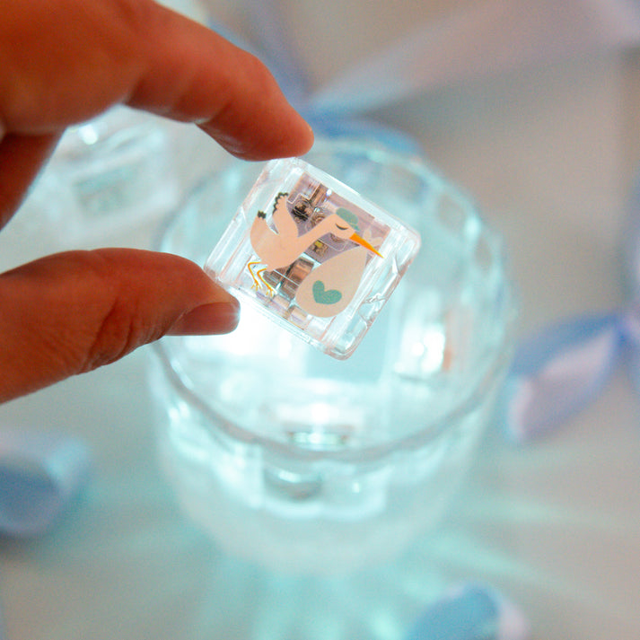 Hand holding a clear square object with a printed design on a blurred background