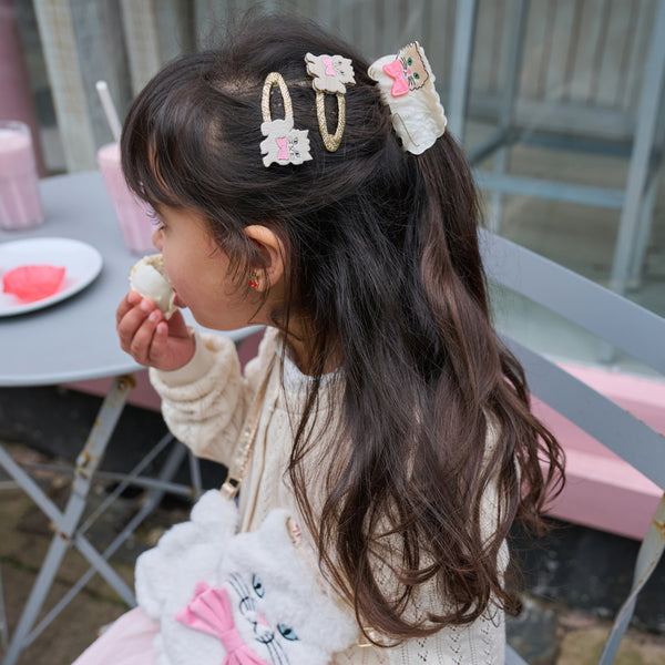 Child with decorative hair clips eating a cookie outdoors
