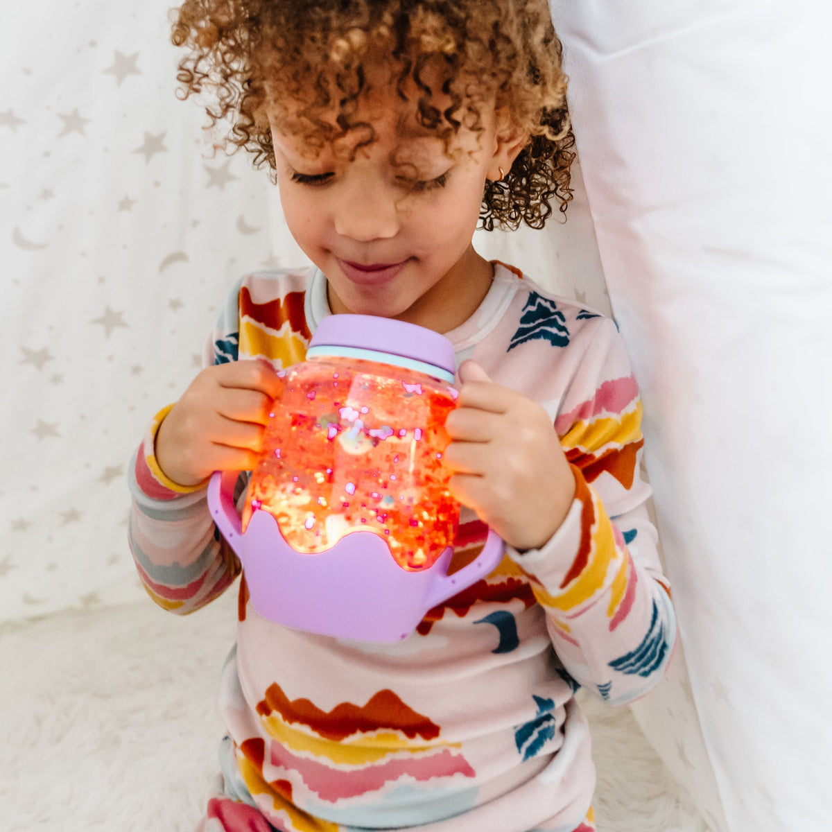 Child holding a colorful light-up toy with a star-patterned background