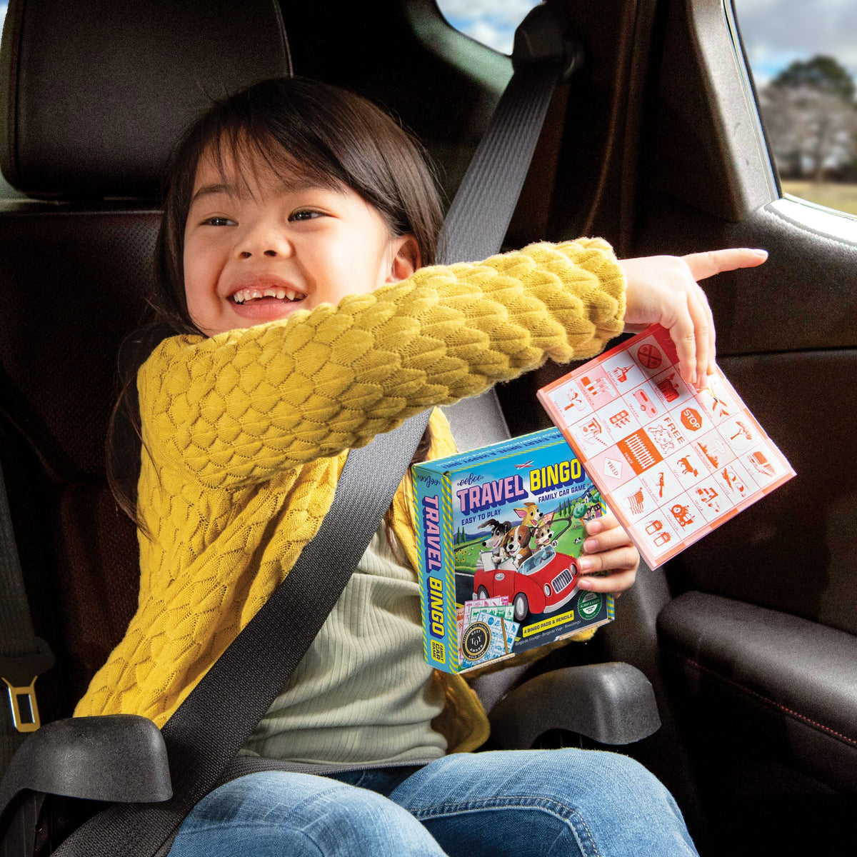 Child in a car seat holding travel games