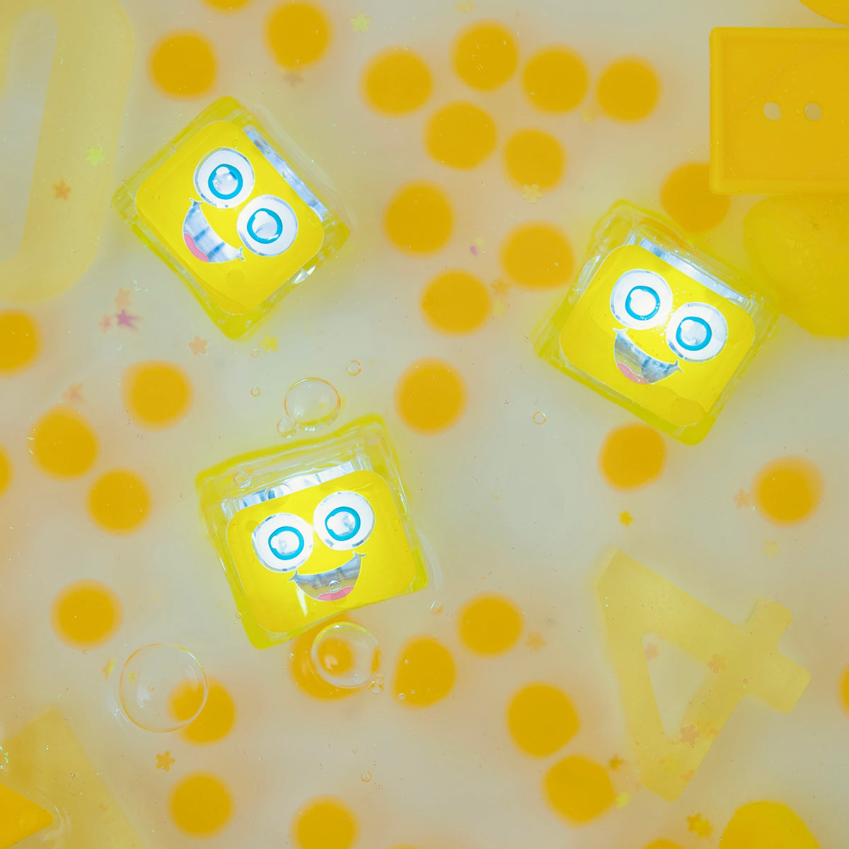 Yellow toy cubes with smiling faces on a yellow and white background