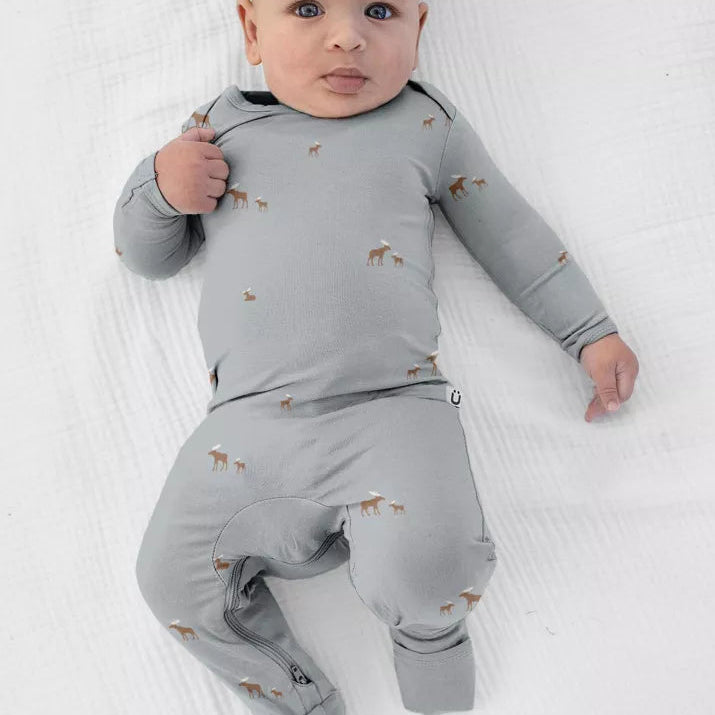 A baby wearing a sage grey günamüna Convertible Footie Pajama patterned with tiny dogs.