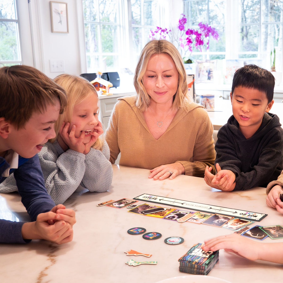 Family playing a board game together in a bright room with large windows.