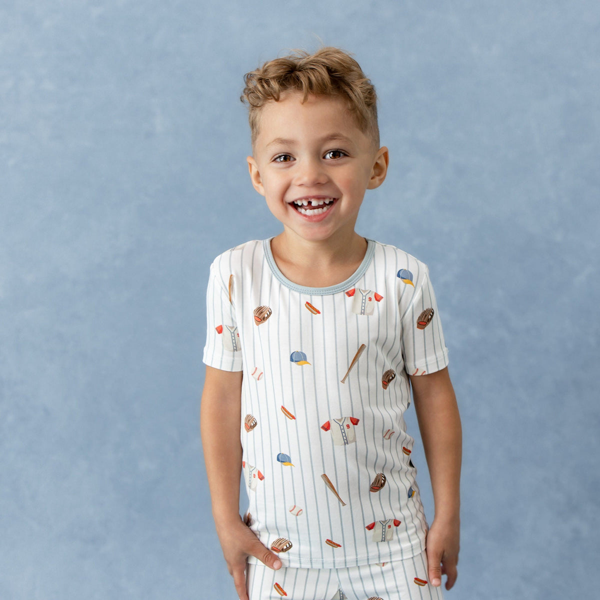 Child wearing a pajama set with sports-themed print against a blue background