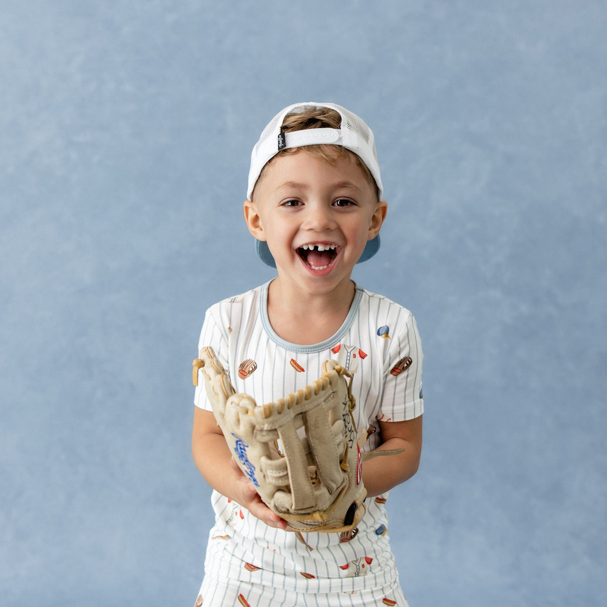 Child holding a baseball glove against a blue background