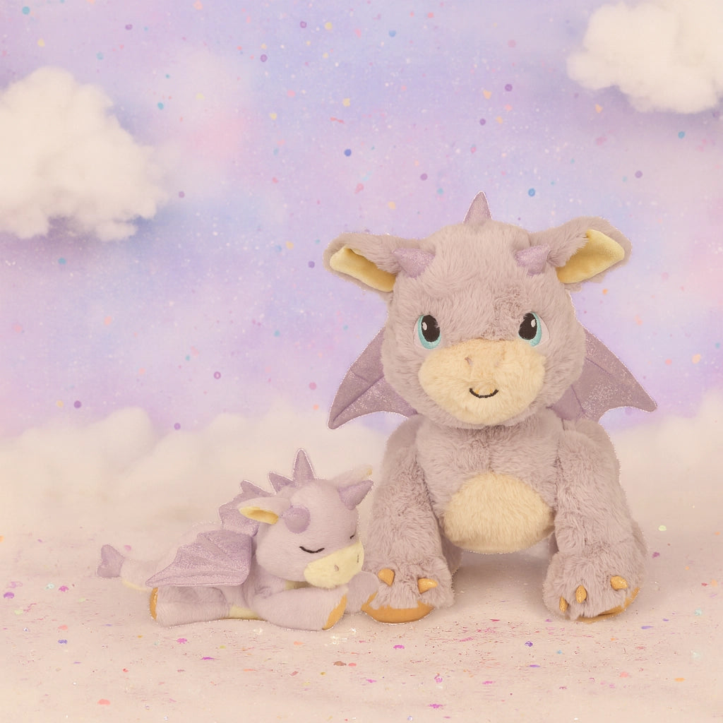Two plush dragon toys on a soft, cloud-like surface with a pastel background.