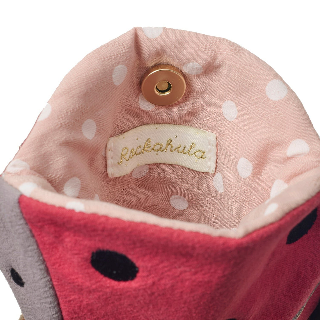 Close-up of a pink polka dot pouch with a visible brand label on a white background