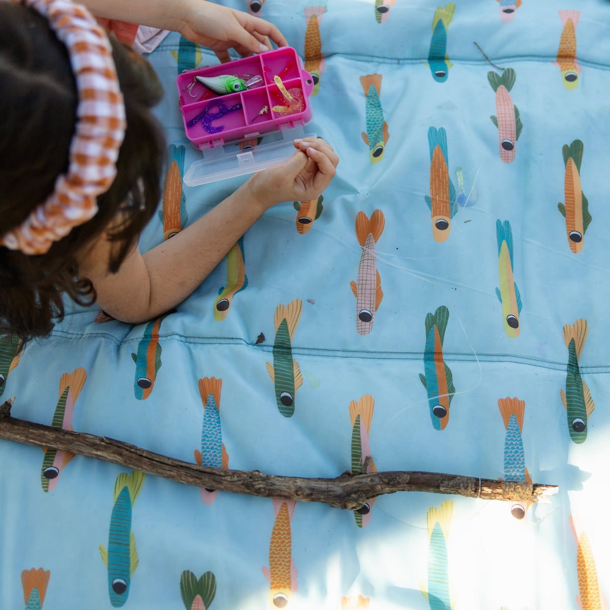 Child playing with fishing toys on a blanket with fish pattern