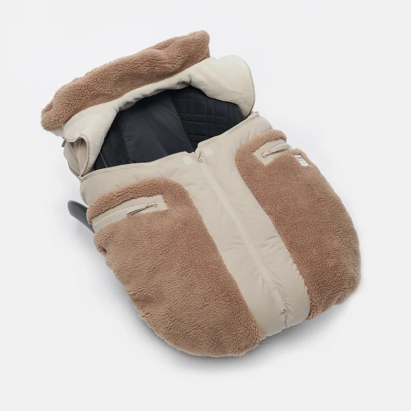 Benji Applique Car Seat Cocoon by 7AM Enfant featuring an oat-colored and brown weatherproof outer shell with plush brown sherpa fleece trim around the collar and a front zipper detail.