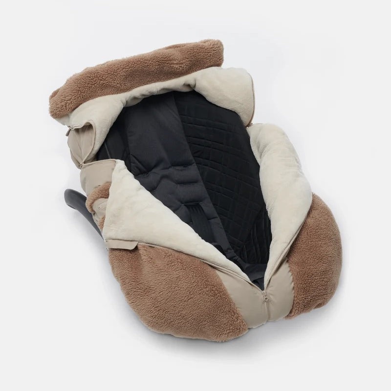 Benji Applique Car Seat Cocoon by 7AM Enfant featuring a dark grey or black weatherproof outer shell, brown sherpa fleece trim around the face opening and zippered side pockets, and a central front zipper.
Concise: Benji Appliq
