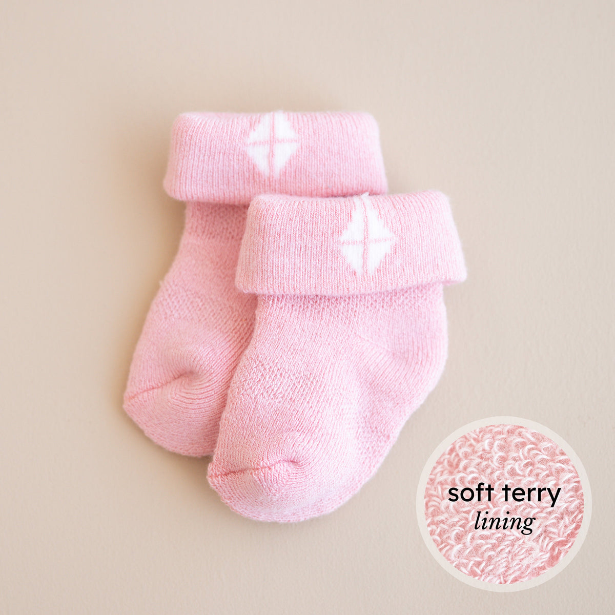 Pink baby socks with soft terry lining on a beige background